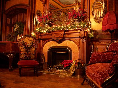 A living room with a fireplace and chairs decorated for christmas at the Governor Henry Lippitt House Museum