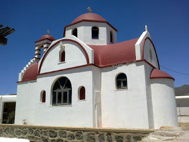 A small white church with a red roof known as Agios Panteleimonas