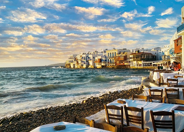 There are tables and chairs on the beach near the ocean in mykonos