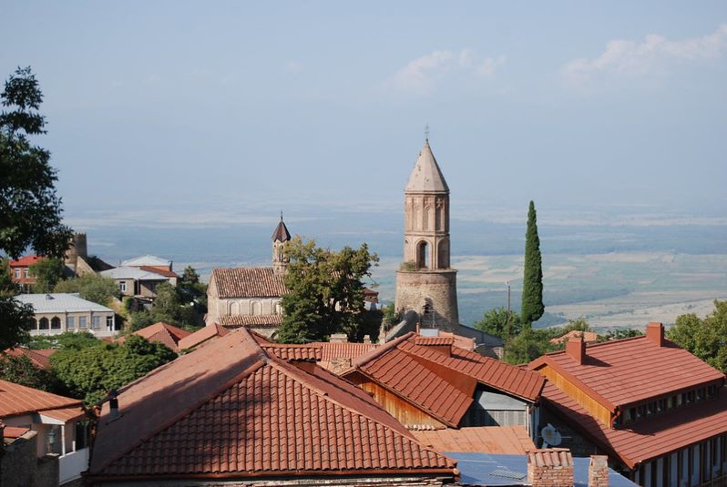A view of a village in Georgia with a clock tower in the distance.