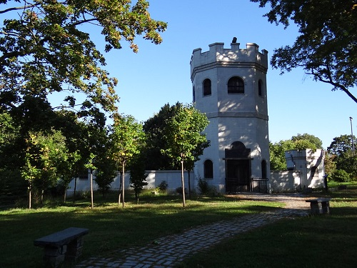 A white tower is surrounded by trees in a park in NYC