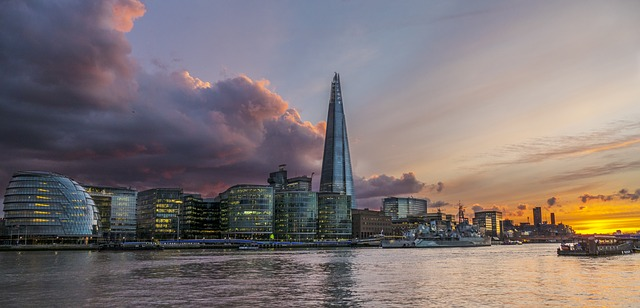 The London skyline with a boat in the water at sunset.