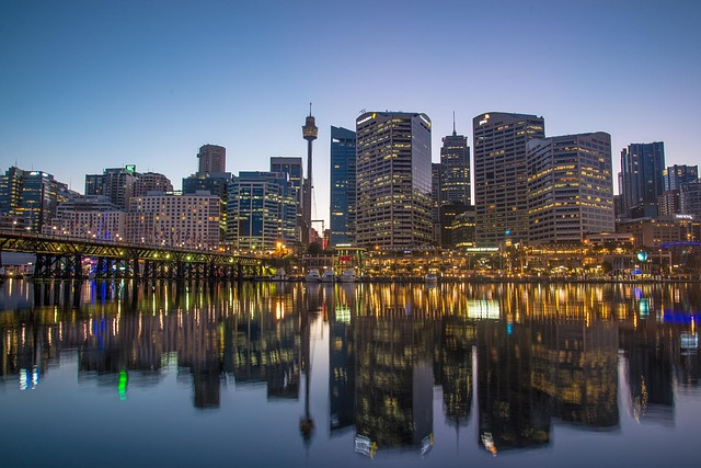 The Sydney skyline is reflected in a body of water at night.