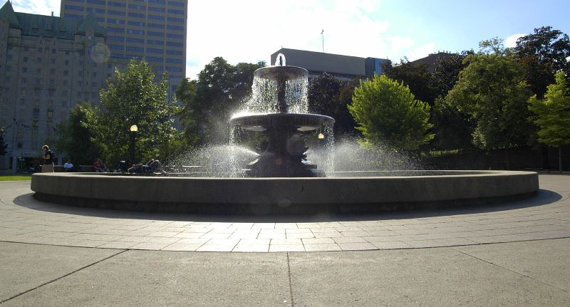 A fountain in a park with a building in the background