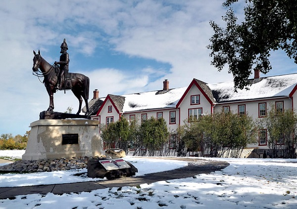 A statue of a man riding a horse in front of Fort Calgary