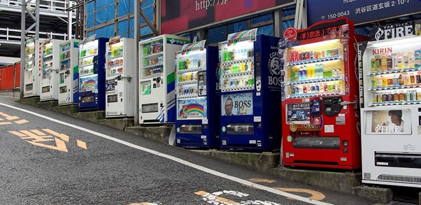 A row of vending machines are lined up on the side of the road in tokyo.