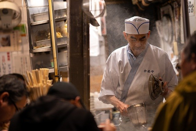 A man in a chef 's uniform is preparing food in a tokyo restaurant.
