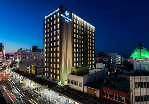 A large building with a lot of windows is lit up at night in Amori City.