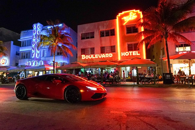 A red sports car is driving down a miami street at night.
