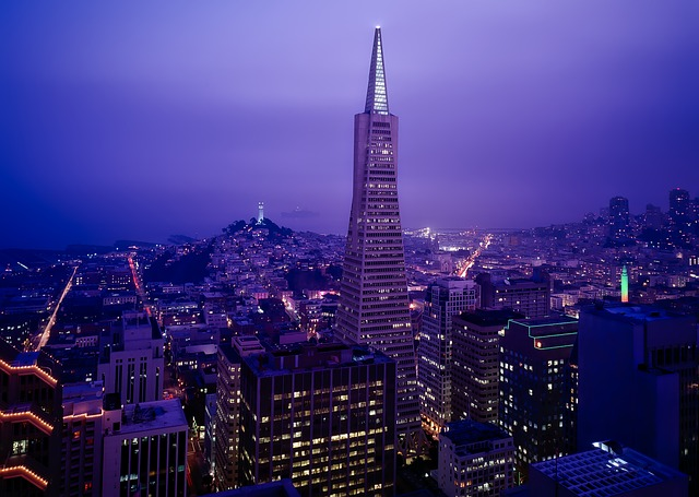 An aerial view of San Francisco at night with a tall building in the foreground