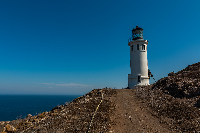 A lighthouse is sitting on top of a hill overlooking the ocean.