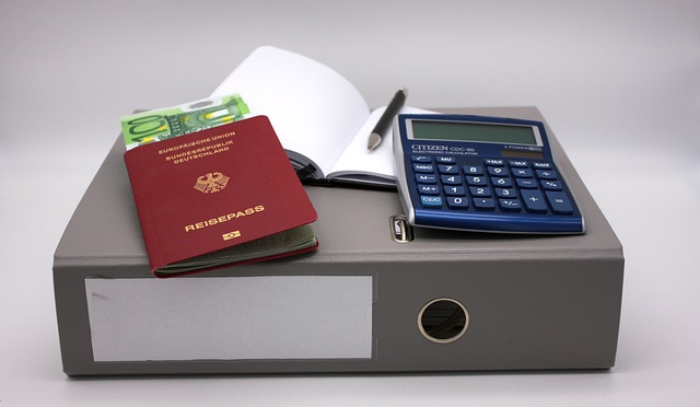 A calculator and a passport are on top of a binder