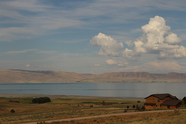 There is a house in the middle of a field next to bear lake in Garden City, Utah