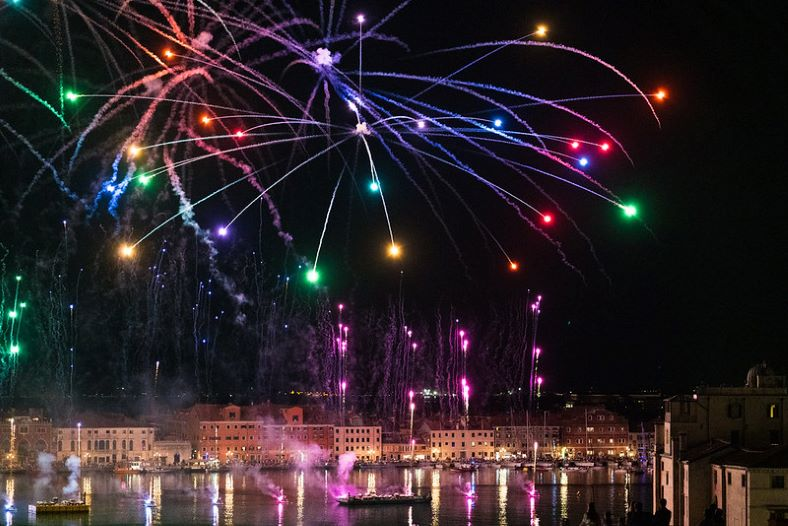 A bunch of fireworks are going off over a body of water