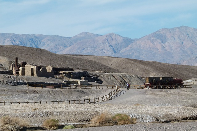 A train is going down a dirt road in Death Valley National Park with mountains in the background.