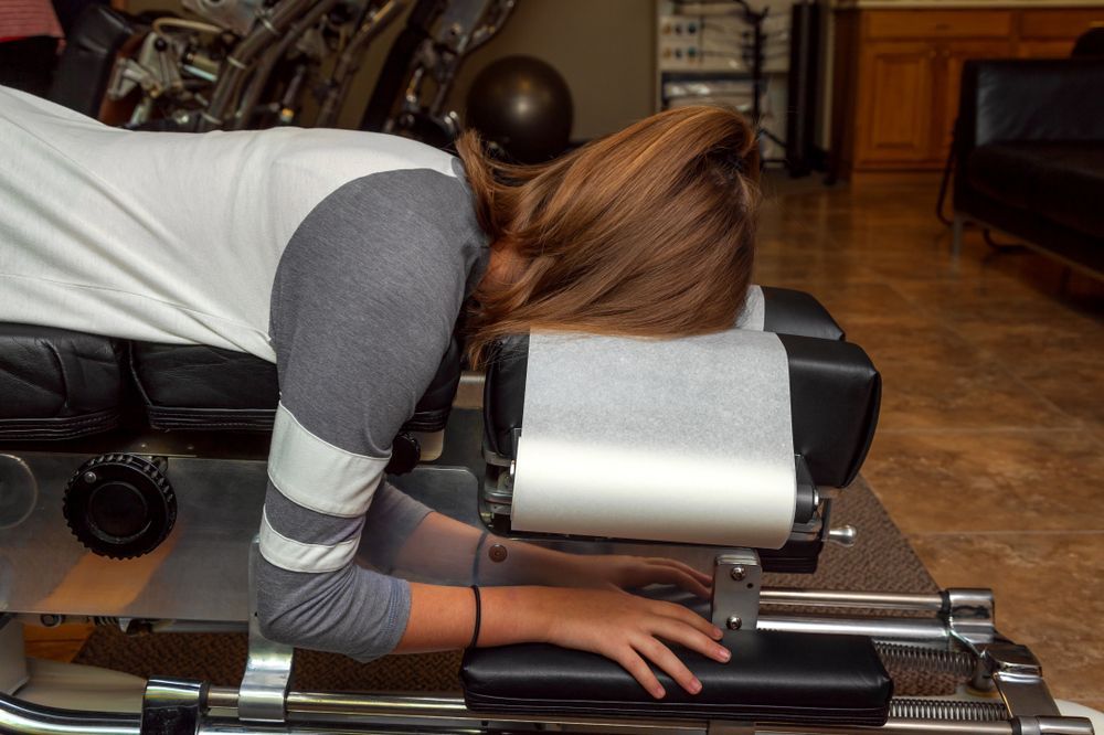 Person Lying Face Down on A Leather Massage Chair — Back Care Gold Coast In Nerang, QLD