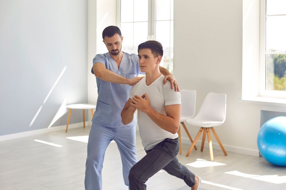 A Man is Being Helped by a Nurse While Doing Exercises in a Room — Back Care Gold Coast In Nerang, QLD