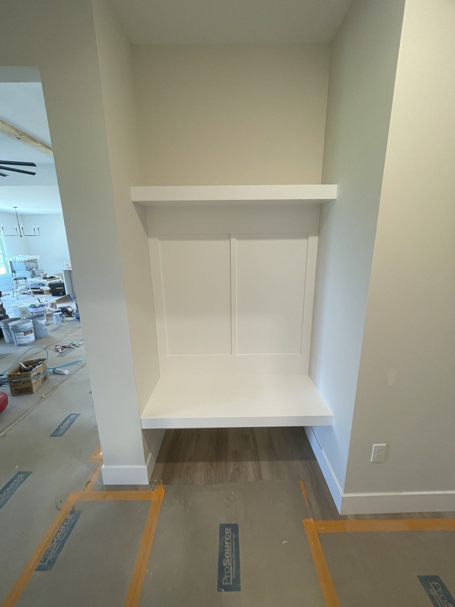 Built-in white shelving niche in a construction area with unfinished floor markings