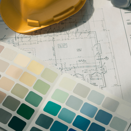 Architectural blueprint with a yellow hard hat and color swatch samples on top