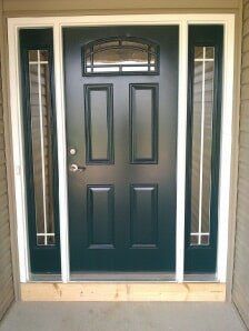 Front door with black panel and sidelights, framed by beige trim and tiled entryway