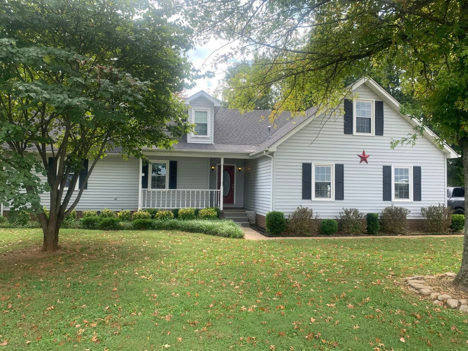 Victorian cottage with a front porch, pastel trim, and flower-filled garden path