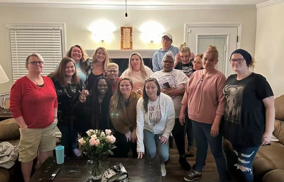 Group of people posing together in a warmly lit living room during a gathering.