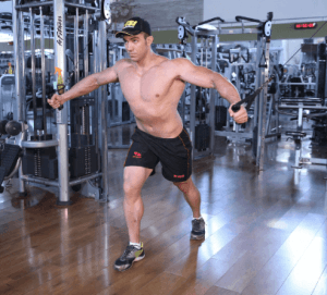 Um homem sem camisa está usando uma máquina em uma academia