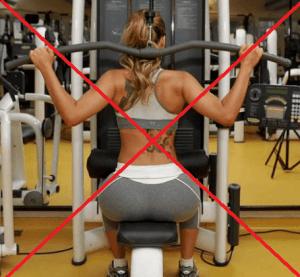 Uma mulher com uma tatuagem nas costas está usando uma máquina em uma academia