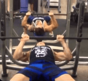 Um homem está levantando uma barra em um banco de uma academia.