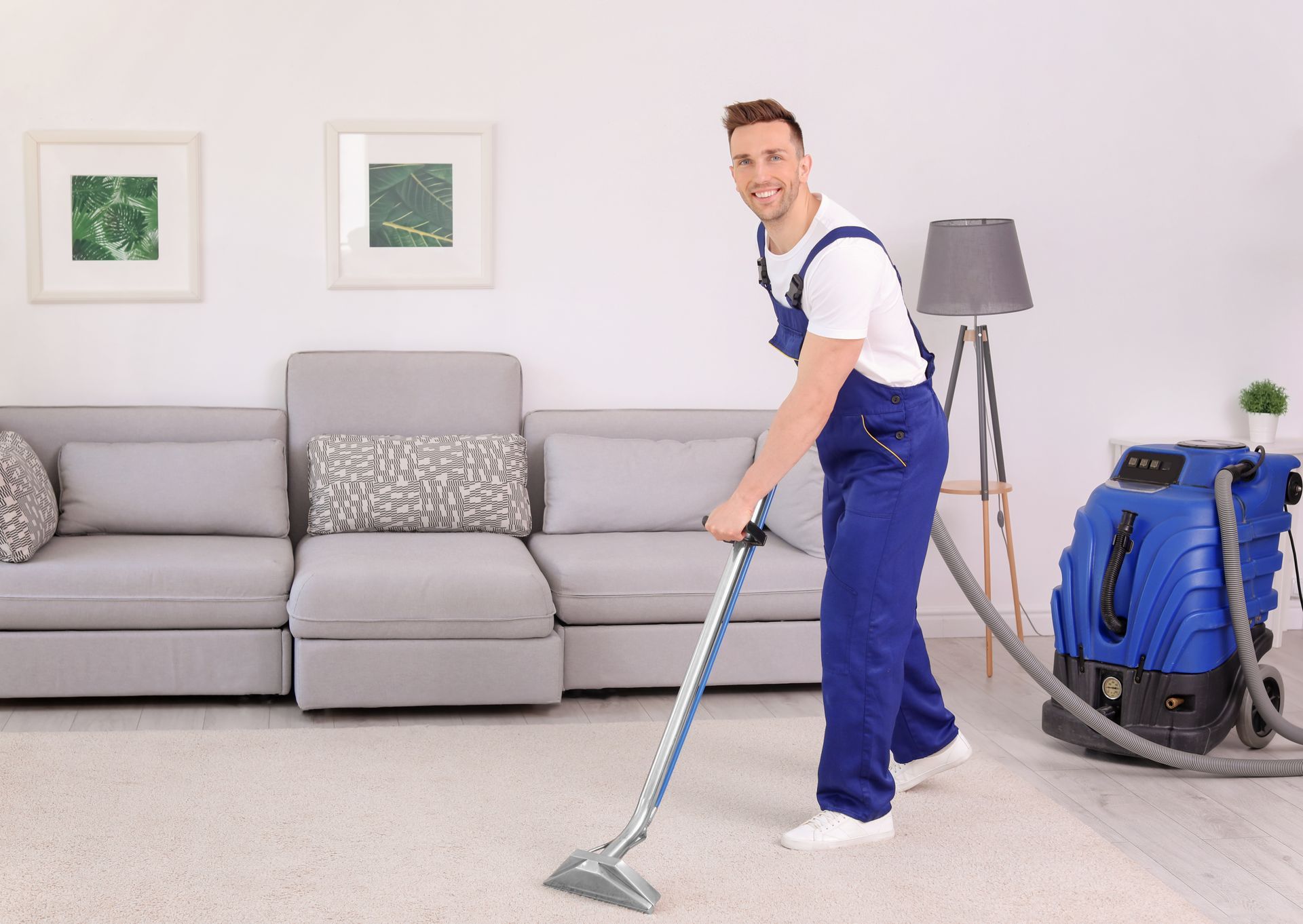 A man is cleaning a carpet with a vacuum cleaner in a living room.