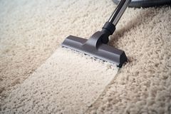 A vacuum cleaner is being used to clean a carpet.
