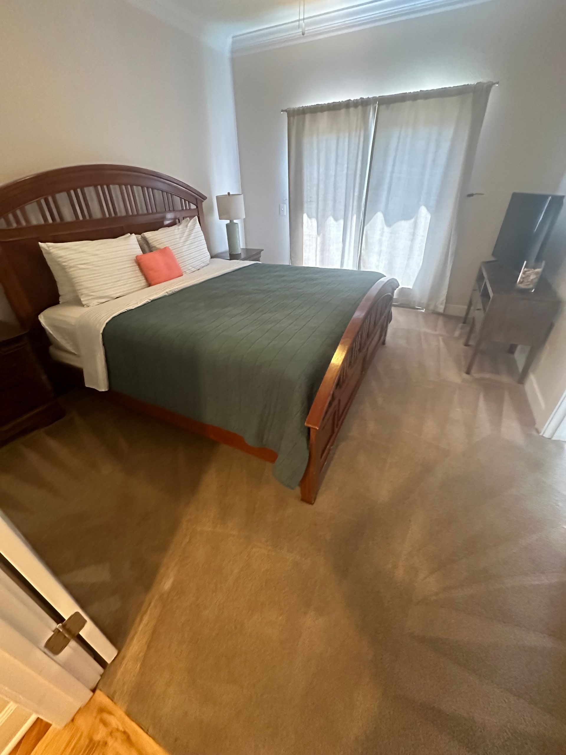 A bedroom with a king size bed and a sliding glass door.