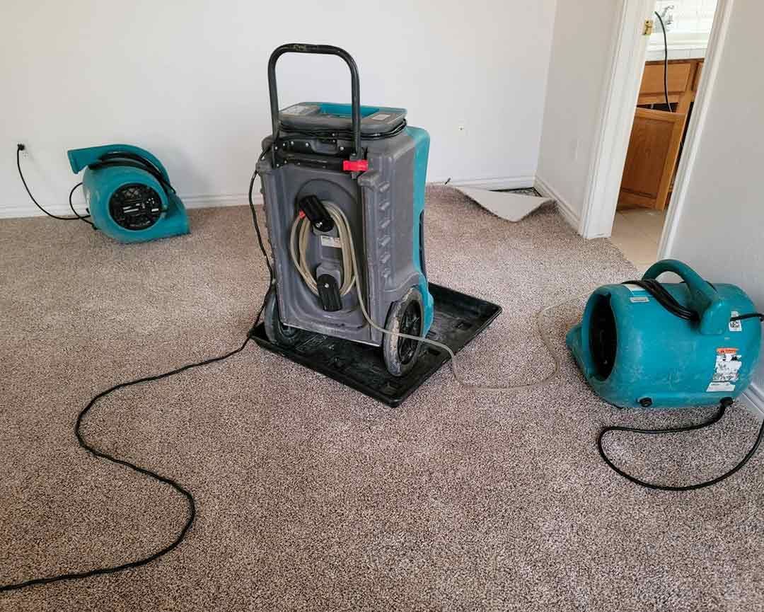 A room with a vacuum cleaner and a blower on the floor.
