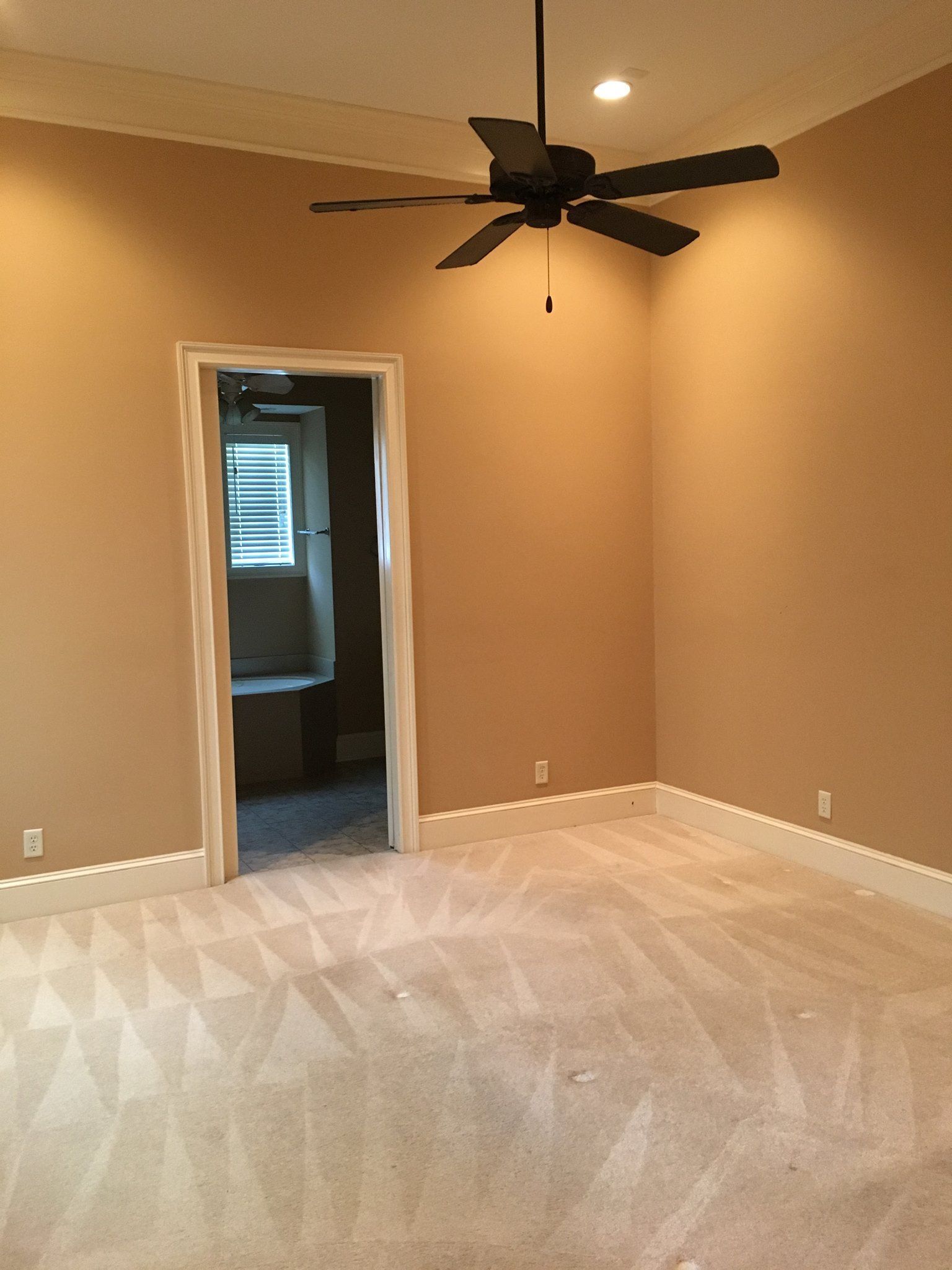 An empty bedroom with a ceiling fan hanging from the ceiling