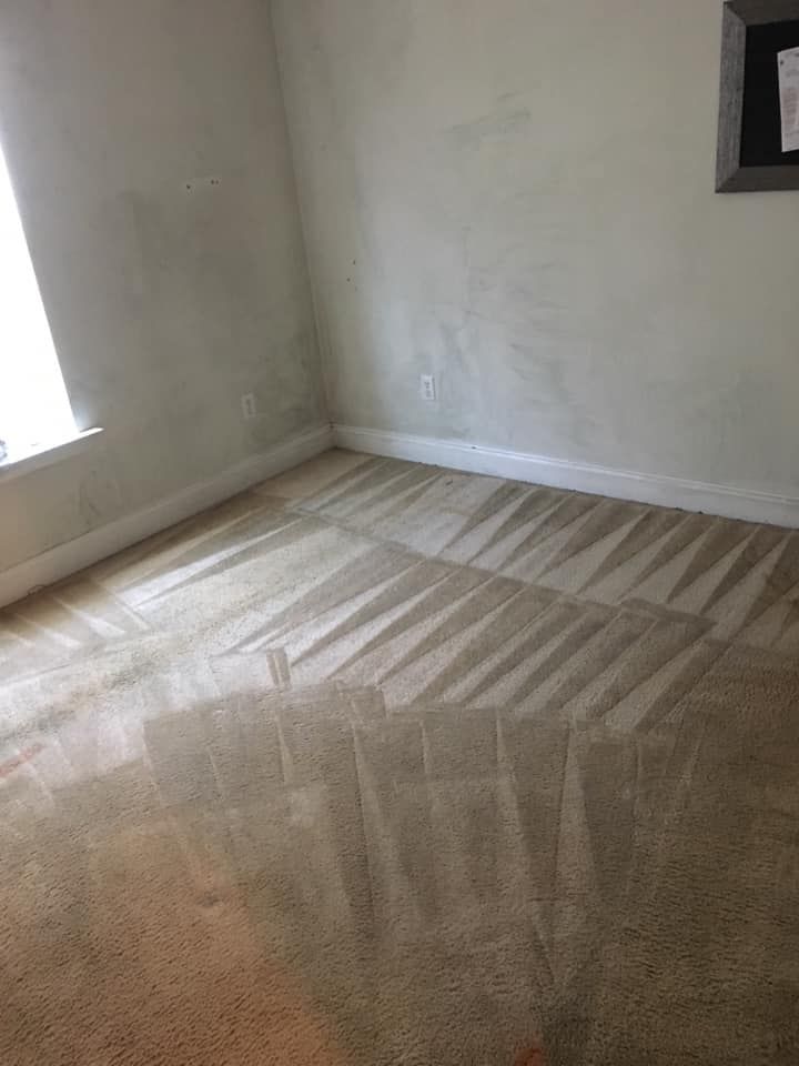 An empty room with a carpeted floor and a window.