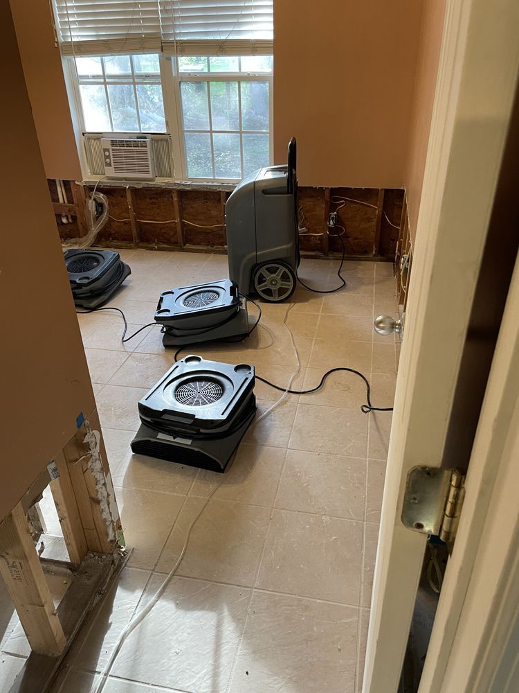 A room with a fan on the floor and a window.