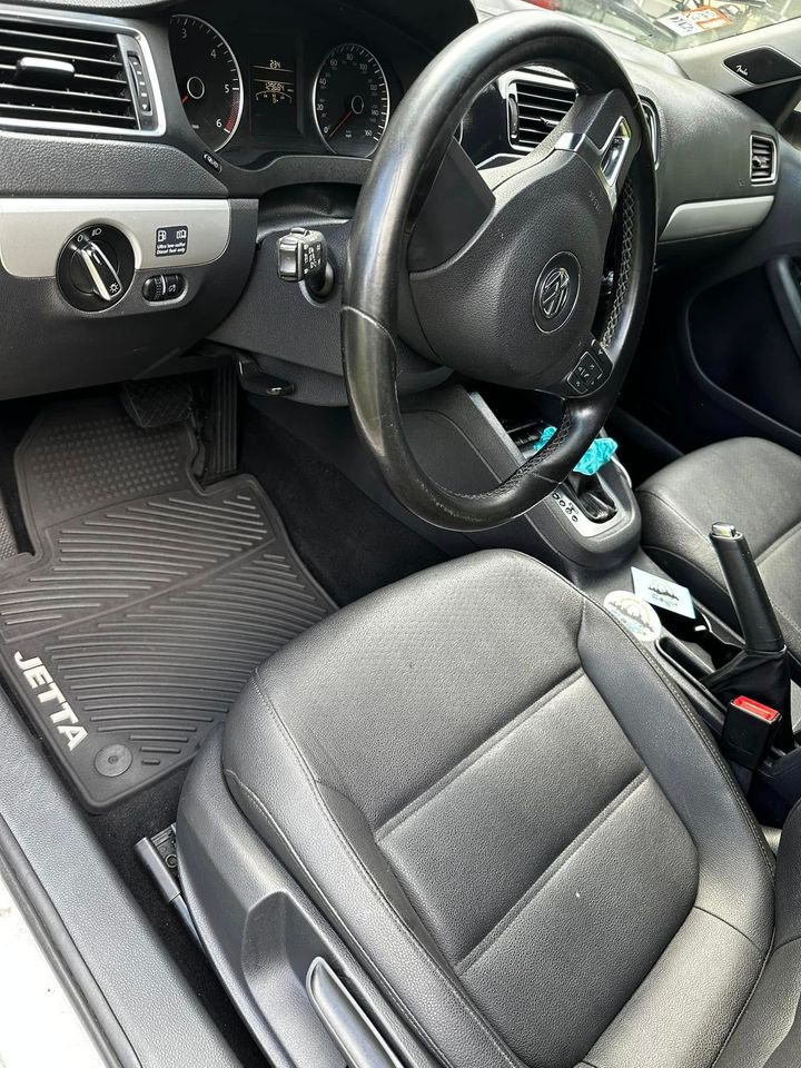 Car interior with right-hand drive, black steering wheel, gray seats, and floor mat.