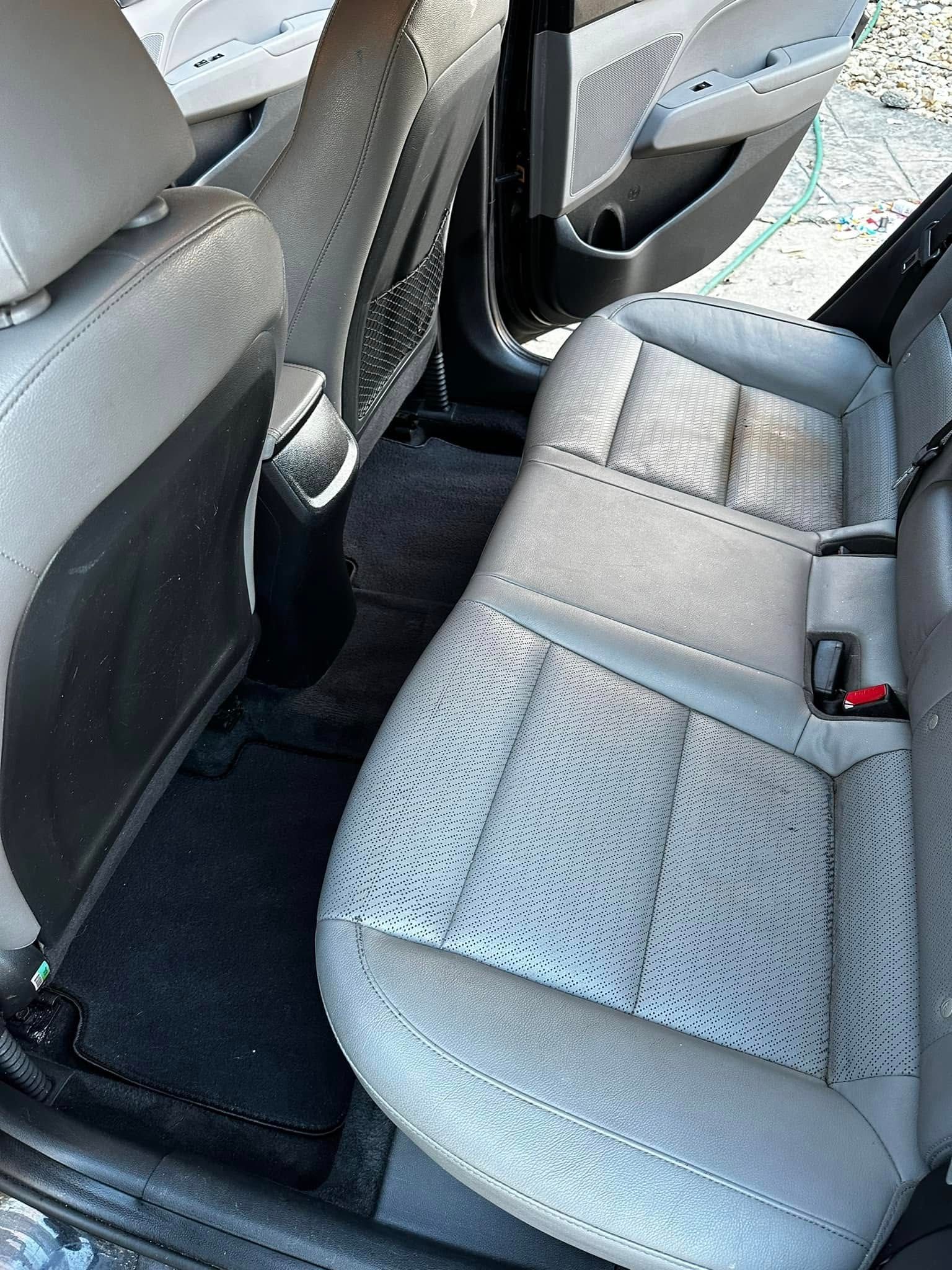 Rear car seat interior with gray upholstery and black floor mats