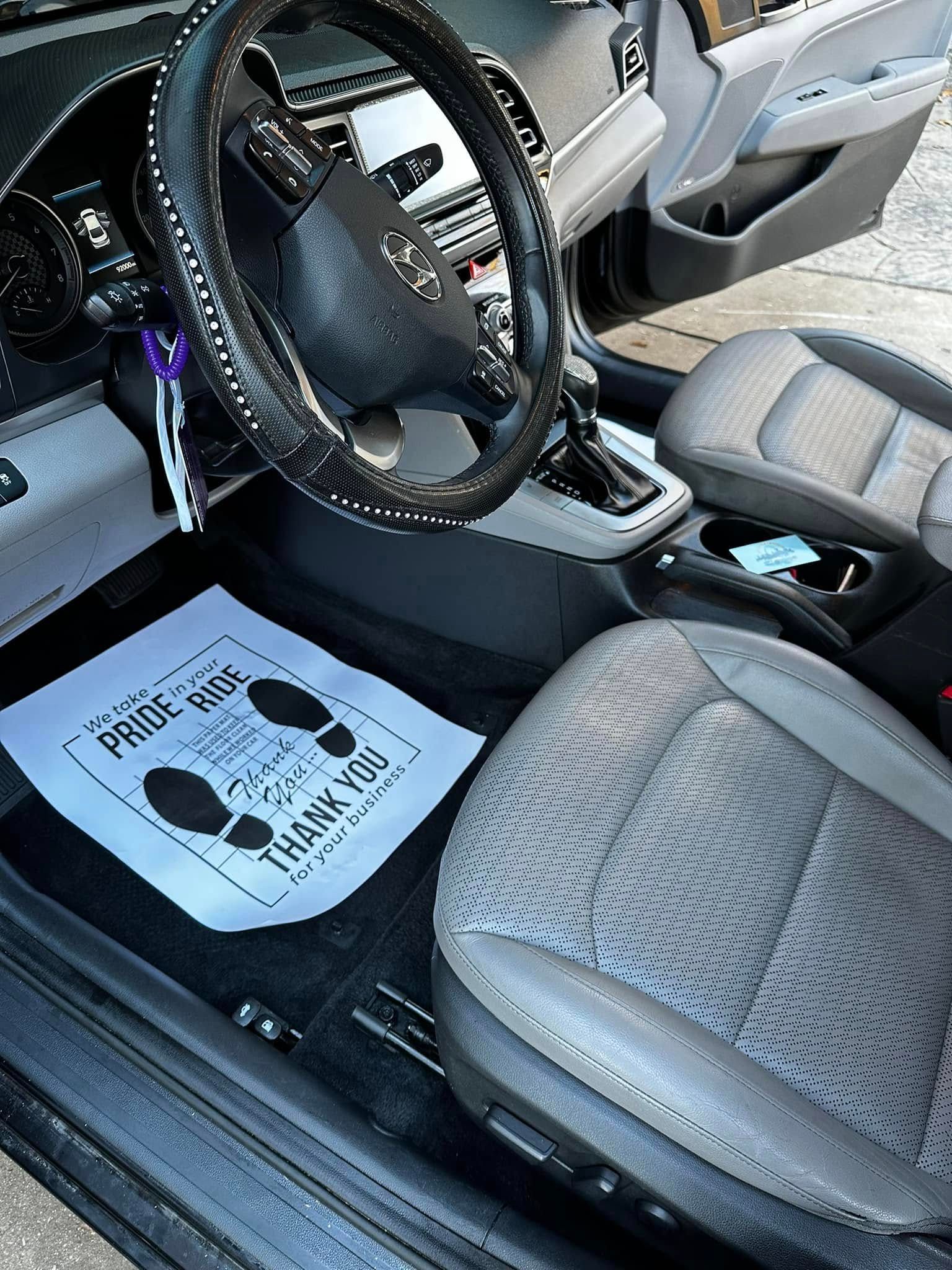 Car interior with gray seats, steering wheel, center console, and a floor mat on the driver's side