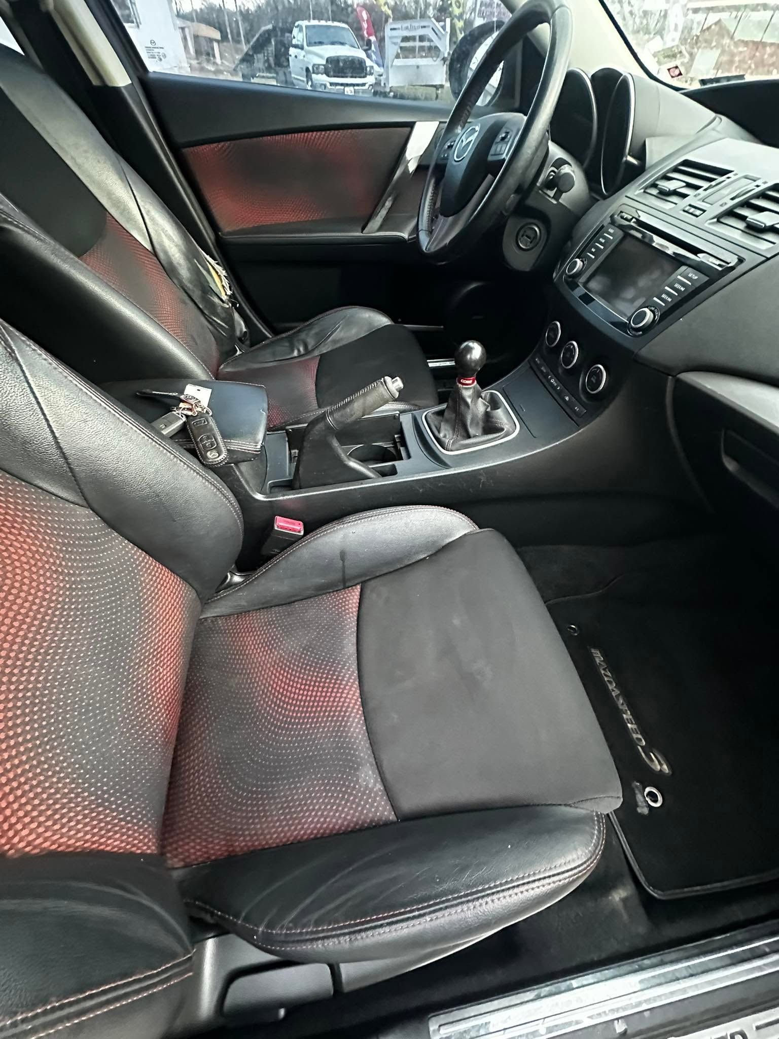 Black car interior with red-accented seats, center console, and steering wheel visible from the passenger side