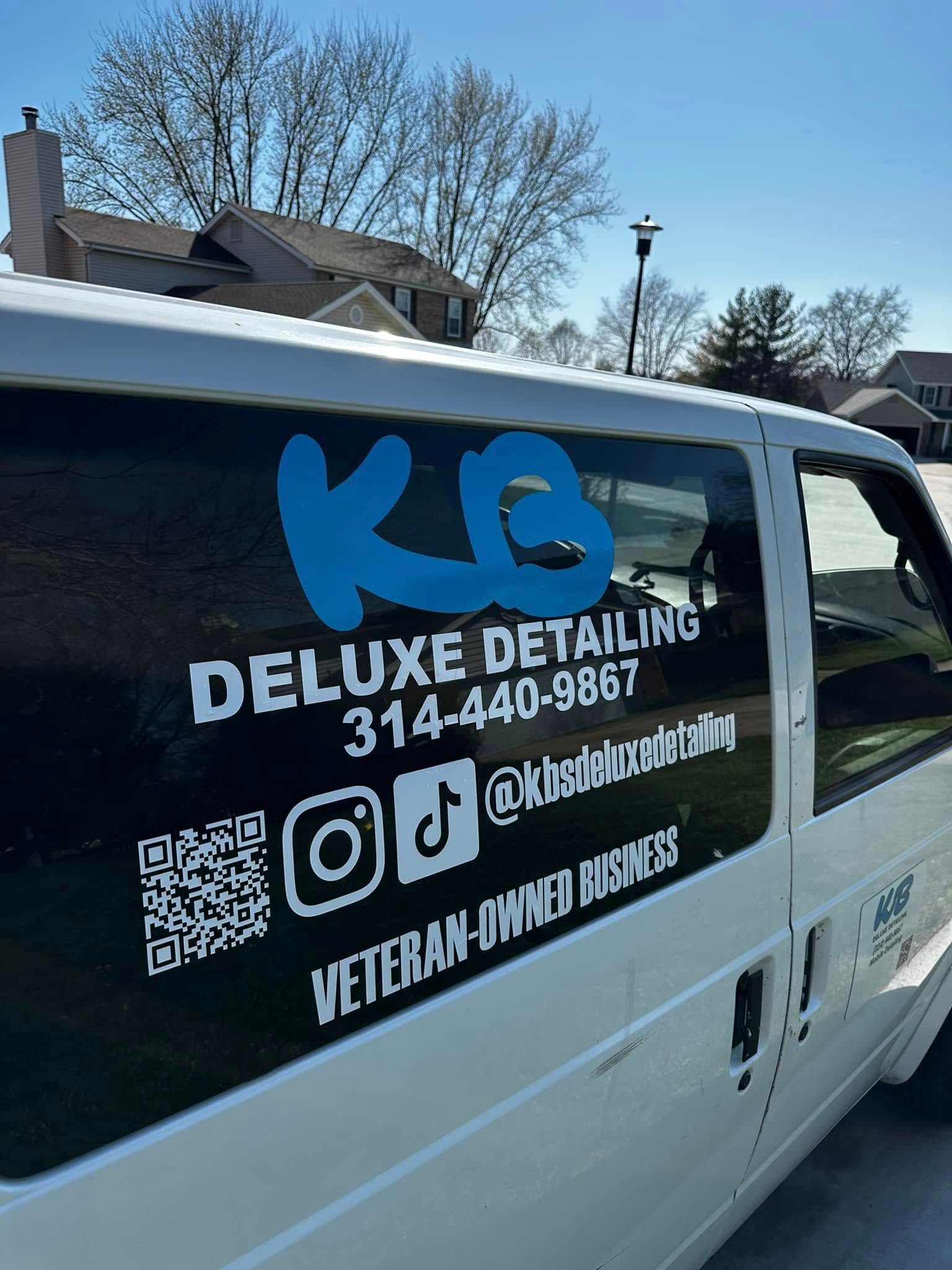 White van with blue “KG Deluxe Detail” auto detailing business logo and contact info on the side.