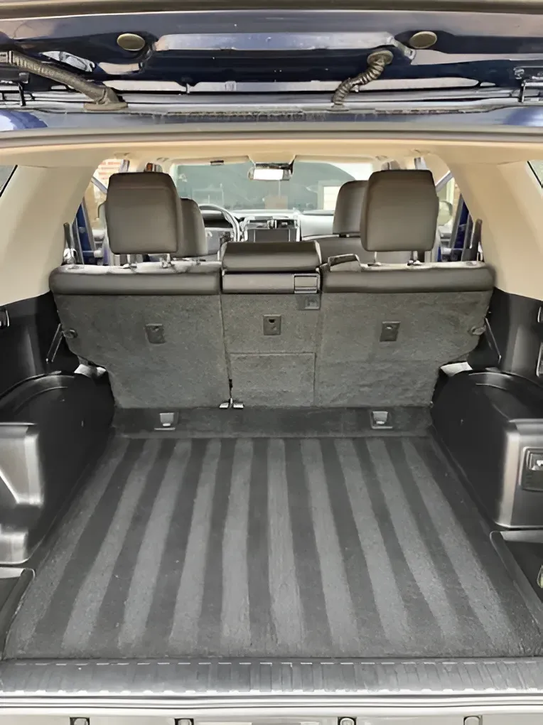 SUV cargo area with open tailgate, black floor mat, and folded rear seats visible ahead