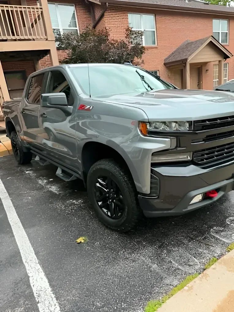 Gray Chevrolet pickup truck parked in an apartment lot with black wheels and red tow hook