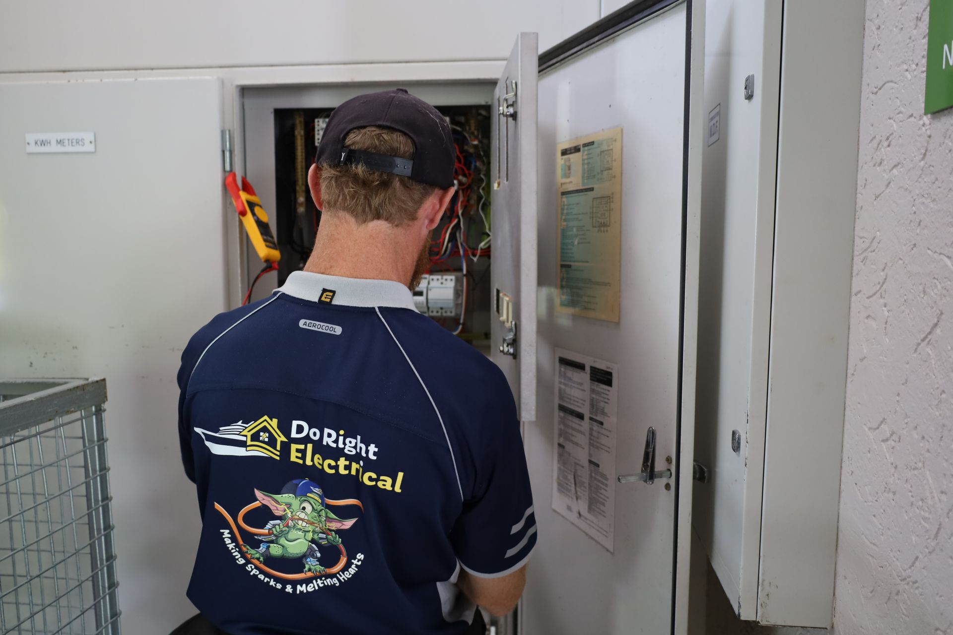 Person Kneeling, Holding Coiled Cable, Illuminating Cabinet — Do Right Electrical in Redlynch, QLD