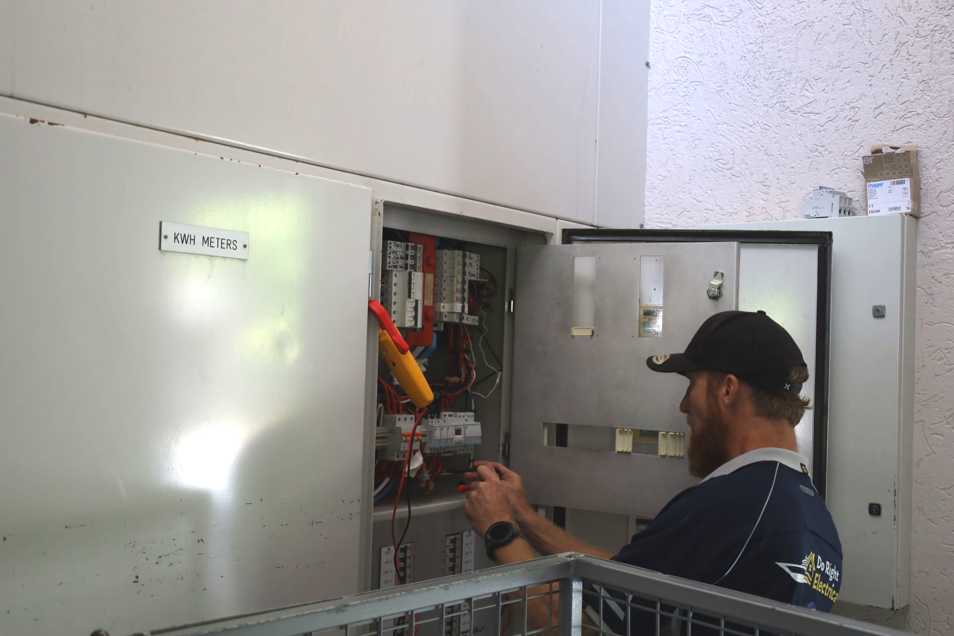Person Working on an Electrical Box, Wires Visible, White Wall — Do Right Electrical in Redlynch, QLD