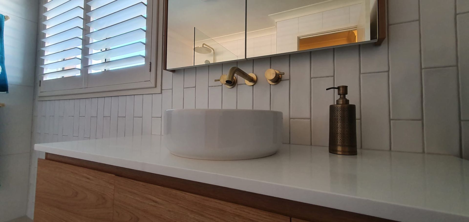 A bathroom with a sink, mirror, and soap dispenser.