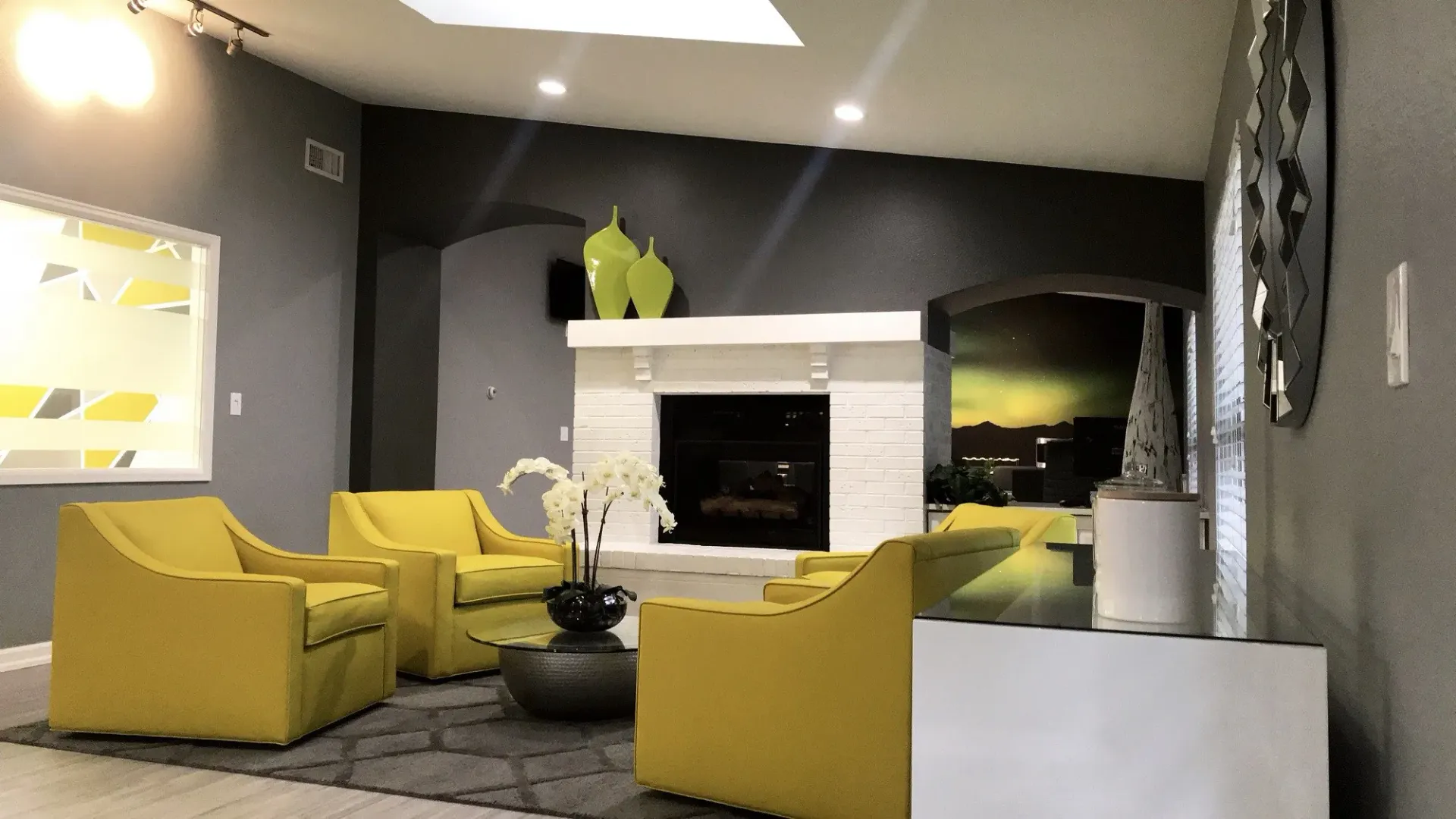 Yellow armchairs in a gray-walled lounge, fireplace with lime green decor, modern, bright space at Westward Heights in Denver, CO.