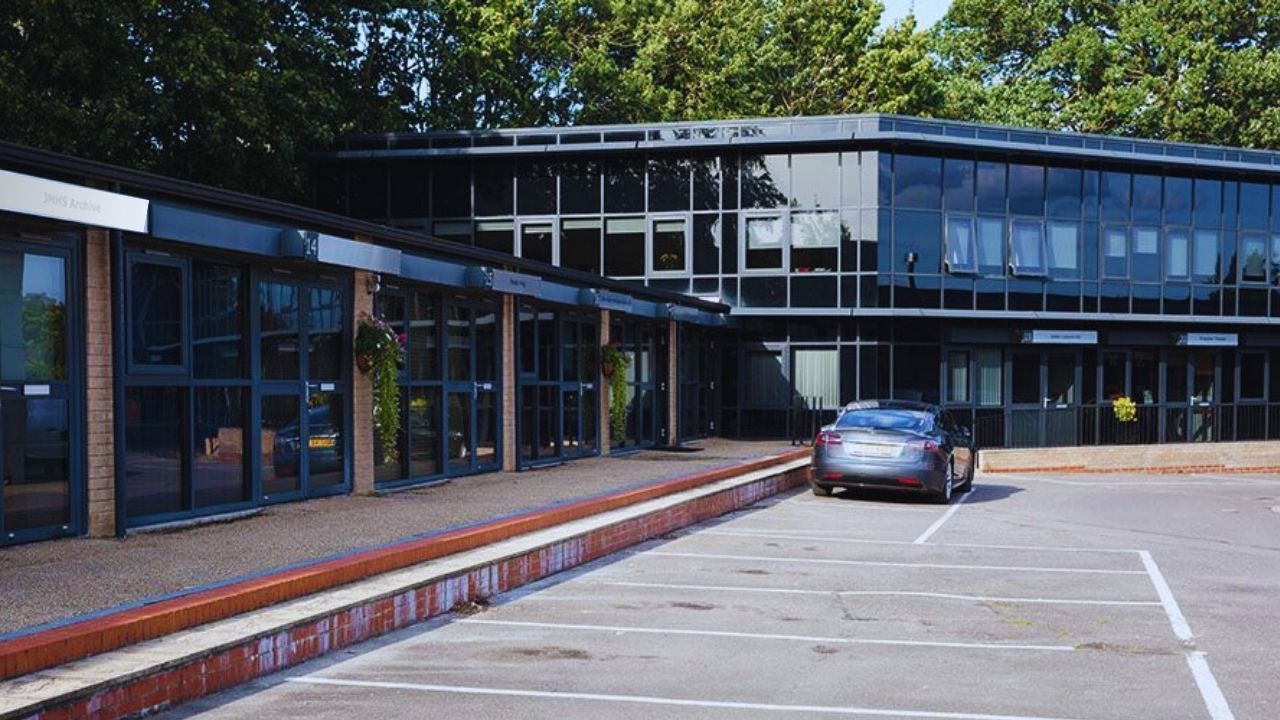 A car is parked in a parking lot in front of a large building.