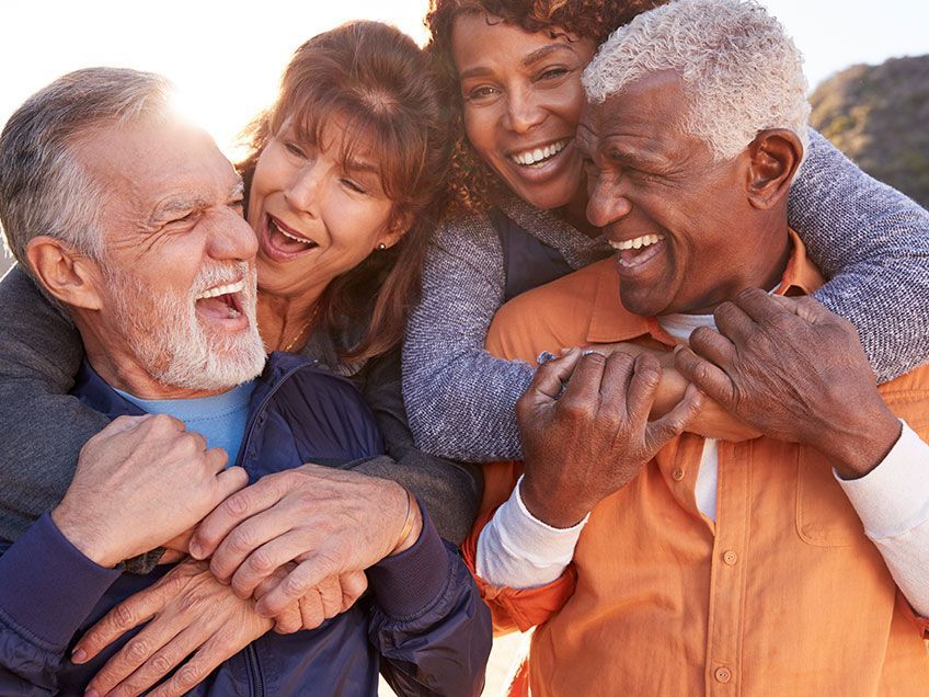 Four friends smiling and hugging outdoors in warm light