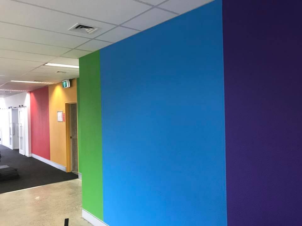 Hallway with walls painted in bright blocks of red, yellow, green, blue, and purple.